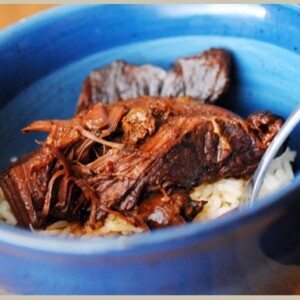 Sweet and spicy Asian boneless ribs in a blue bowl served with white rice.