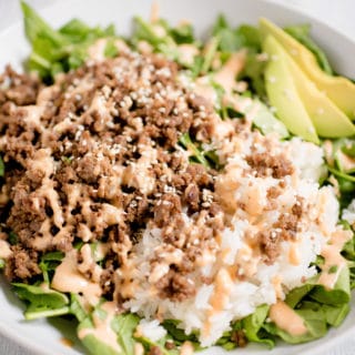 Korean Beef Bowl with rice, spicy mayo and avocado on top of spinach