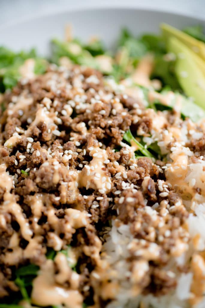 korean beef on top of white rice topped with white sesame seeds and spicy mayo