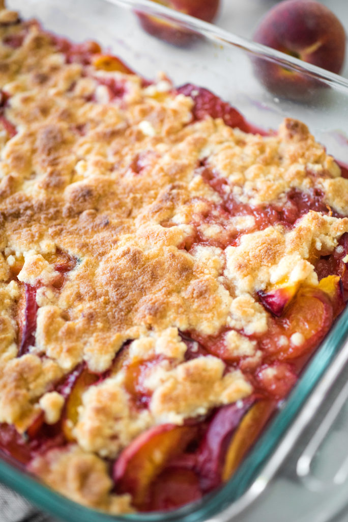 up close shot of the peach cobbler in a glass casserole dish