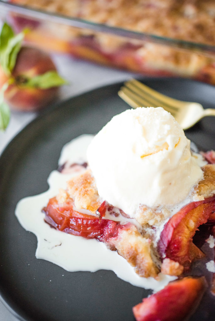 up close shot of peach cobbler with a scoop of vanilla ice cream