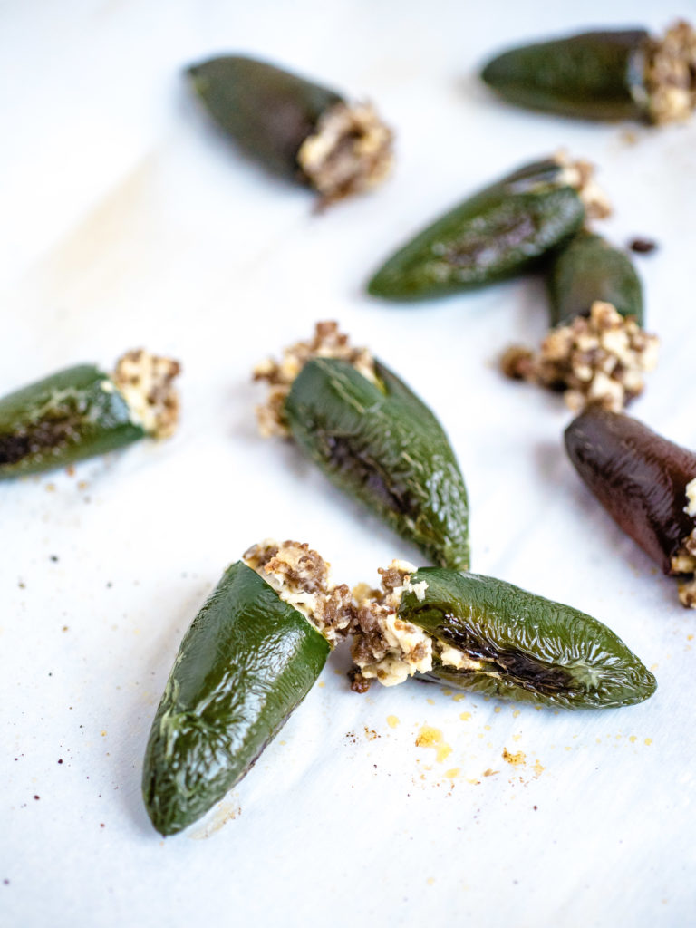 picture of several oven roasted stuffed jalapenos laying on parchment paper