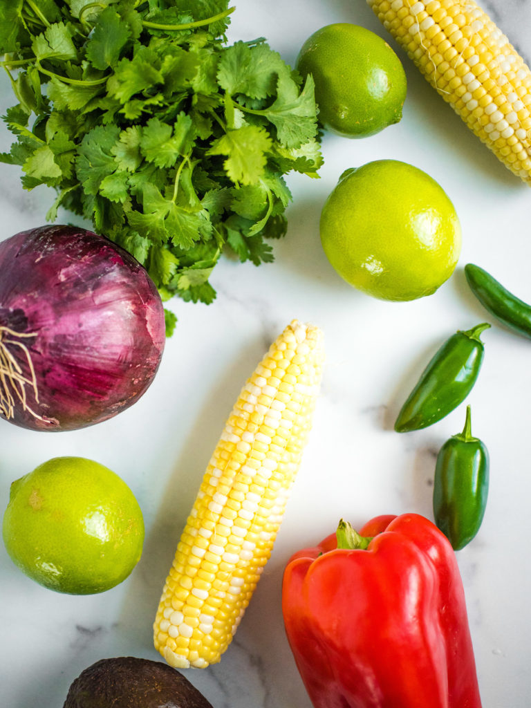 overhead shot of corn, lime, jalapeno, cilantro, red onion, red bell pepper and avocado