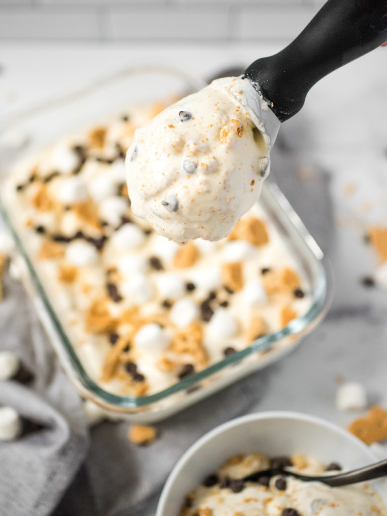 scoop full of ice cream in the foreground with the container of ice cream in the background
