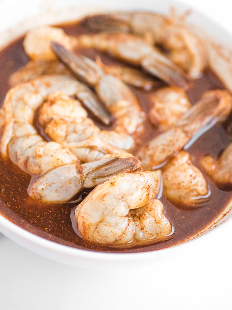 raw shrimp in a white bowl with marinade