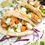 chili lime shrimp tacos in charred white corn tortillas with cabbage slaw and avocado cilantro dressing
