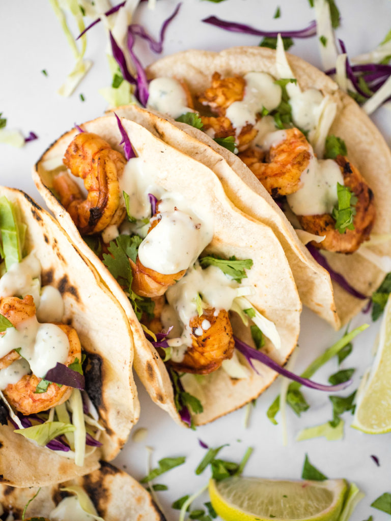 chili lime shrimp tacos in charred white corn tortillas with cabbage slaw and avocado cilantro dressing