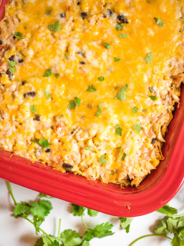up close shot of tex-mex chicken and rice casserole with cilantro and cheese in a red casserole dish