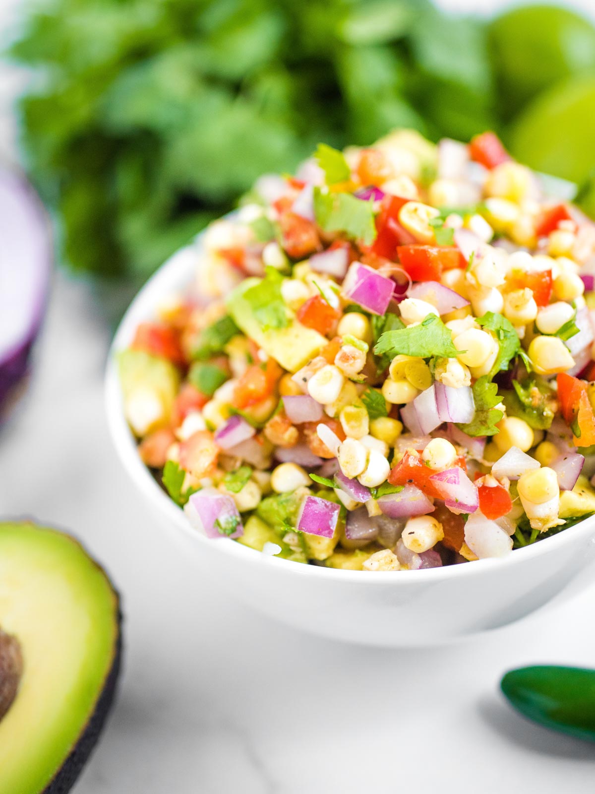 up close view of avocado corn salsa surrounded by additional ingredients