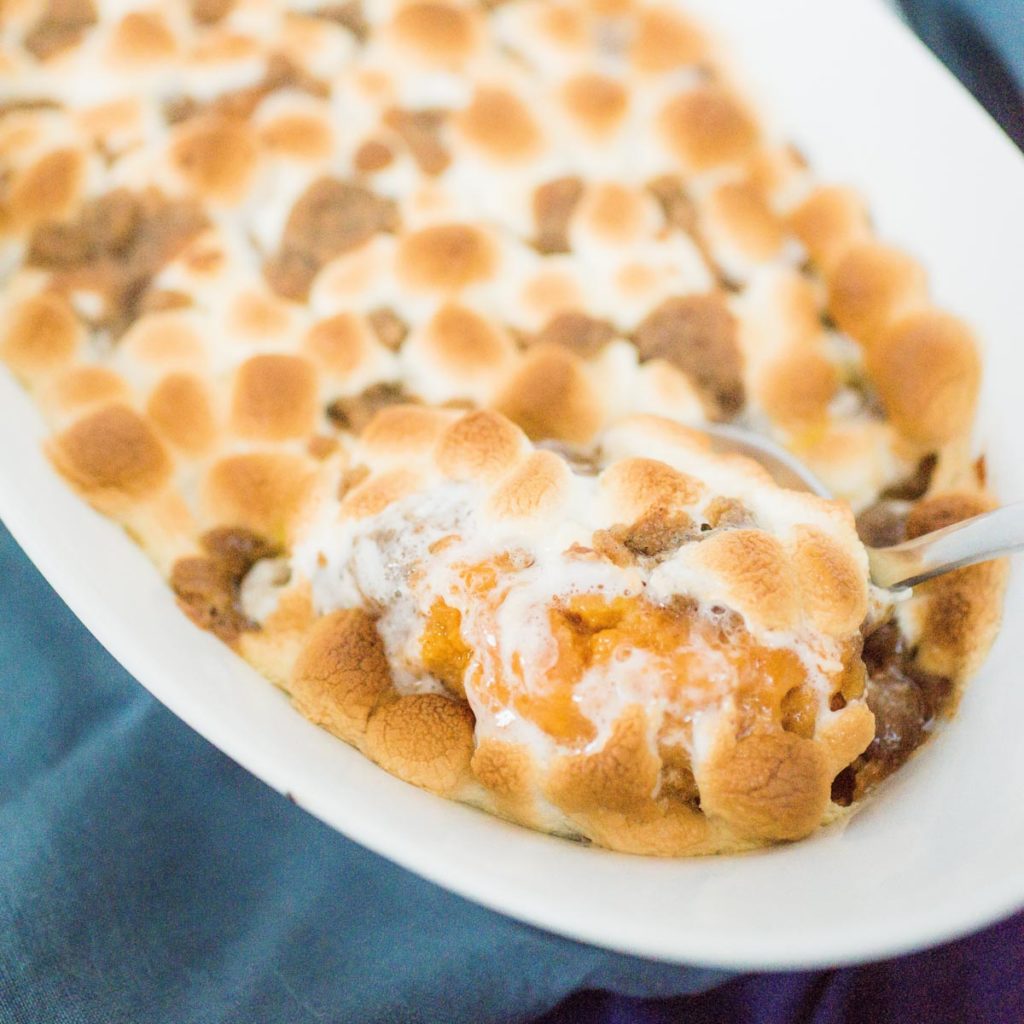 sweet potato casserole being scooped out of a baking dish