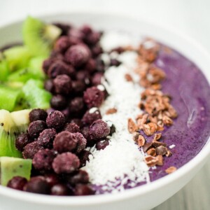 blueberry banana smoothie bowl in a white bowl with toppings