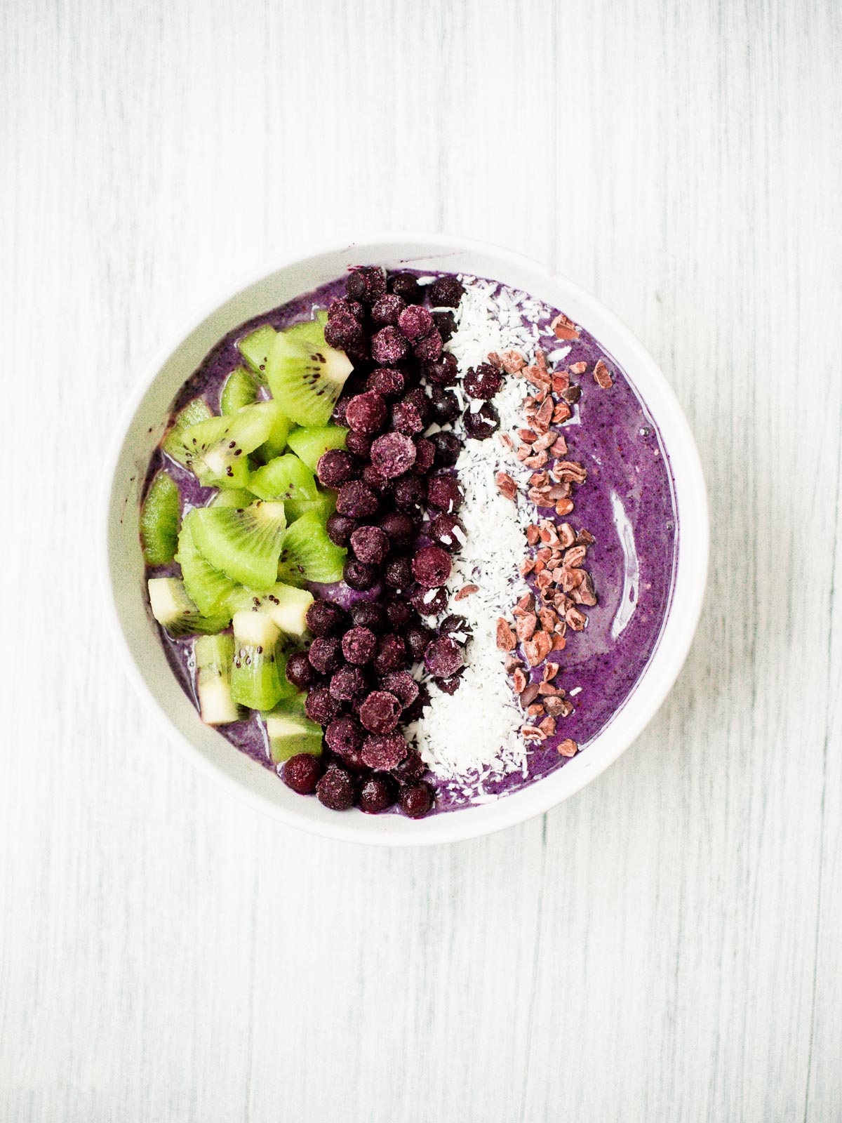 blueberry banana smoothie bowl in a white bowl with toppings