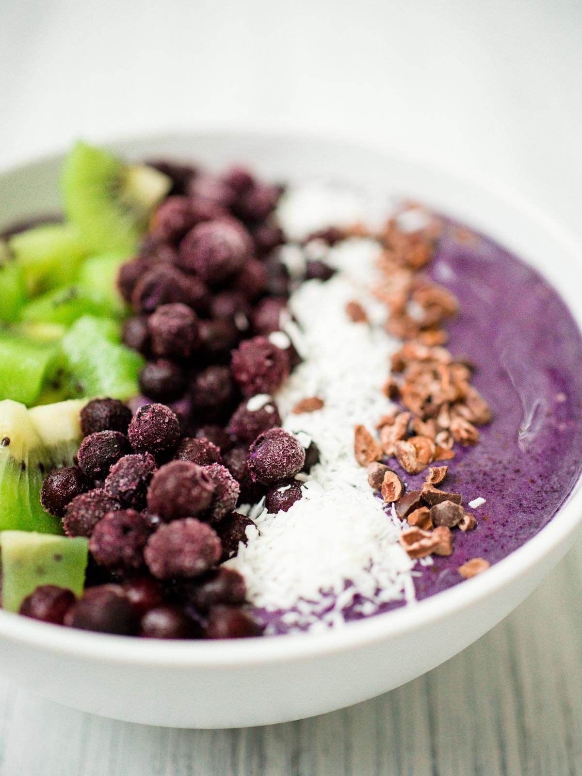 blueberry banana smoothie bowl in a white bowl with toppings