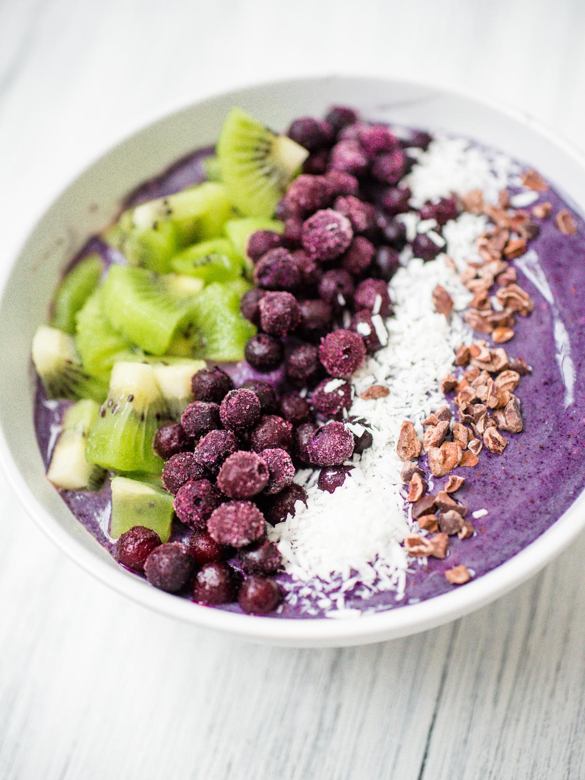 blueberry banana smoothie bowl in a white bowl with toppings