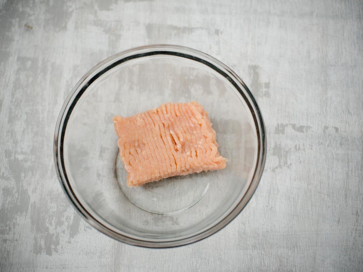 ground raw chicken in a glass bowl