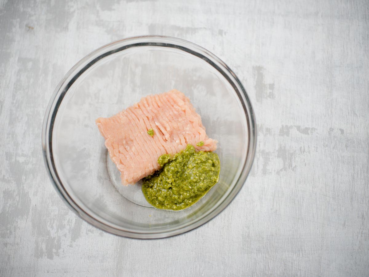 raw chicken and pesto in glass bowl