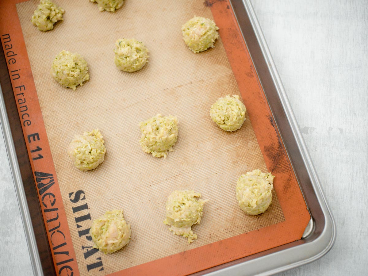 raw chicken pesto meatballs on a baking shit lined with a silpat