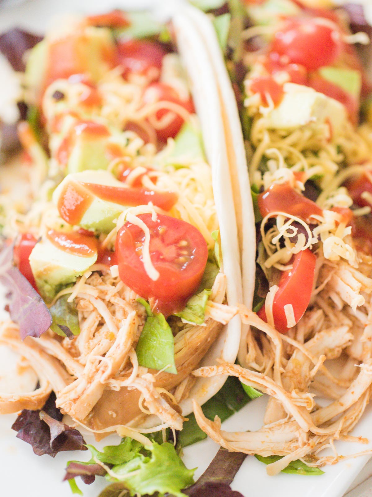 crockpot chicken tacos on a white plate with toppings