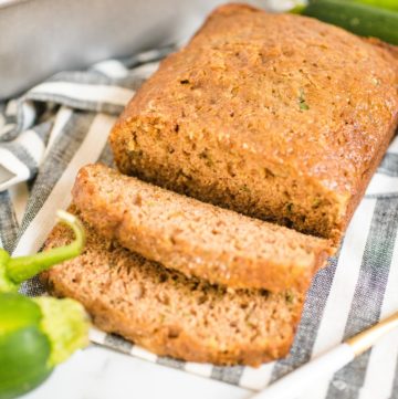 sliced loaf of green chile zucchini bread on a striped cloth
