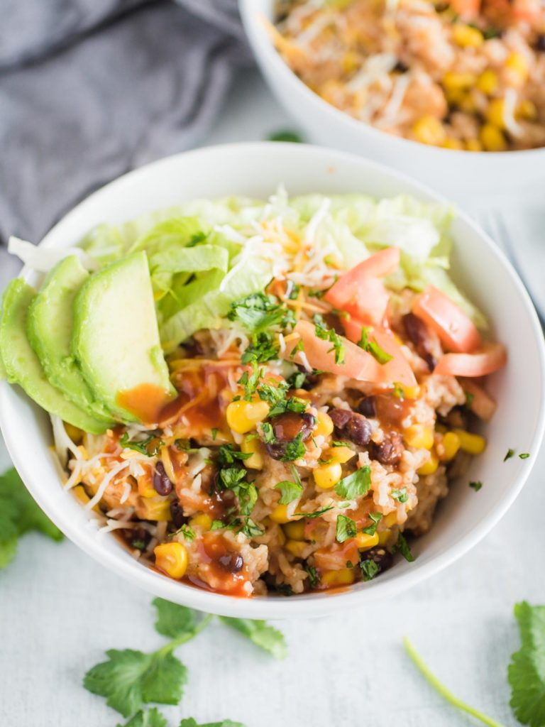 a white bowl full of instant pot chicken burrito bowl with toppings