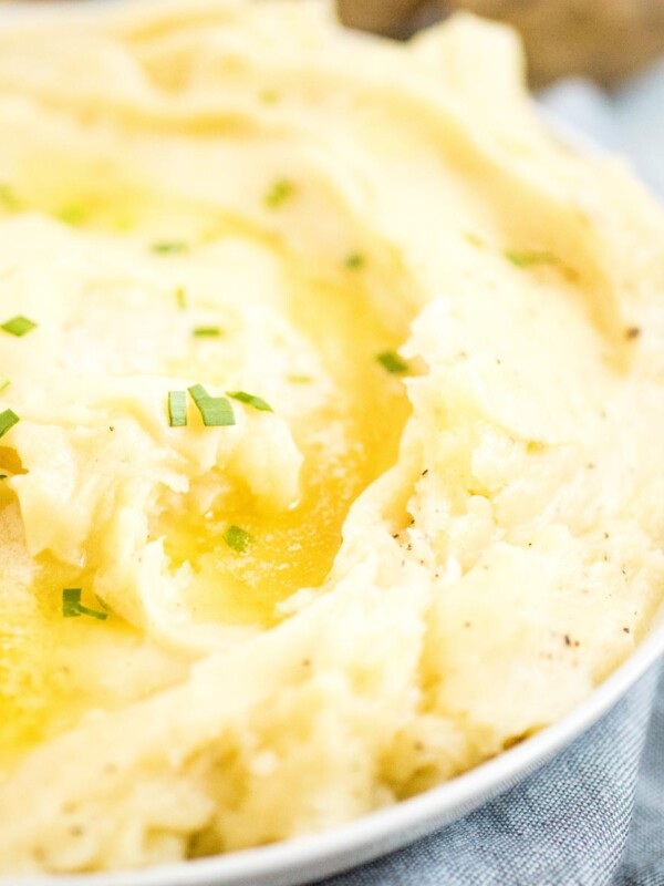 mashed potatoes in white dish topped with melted butter and chives