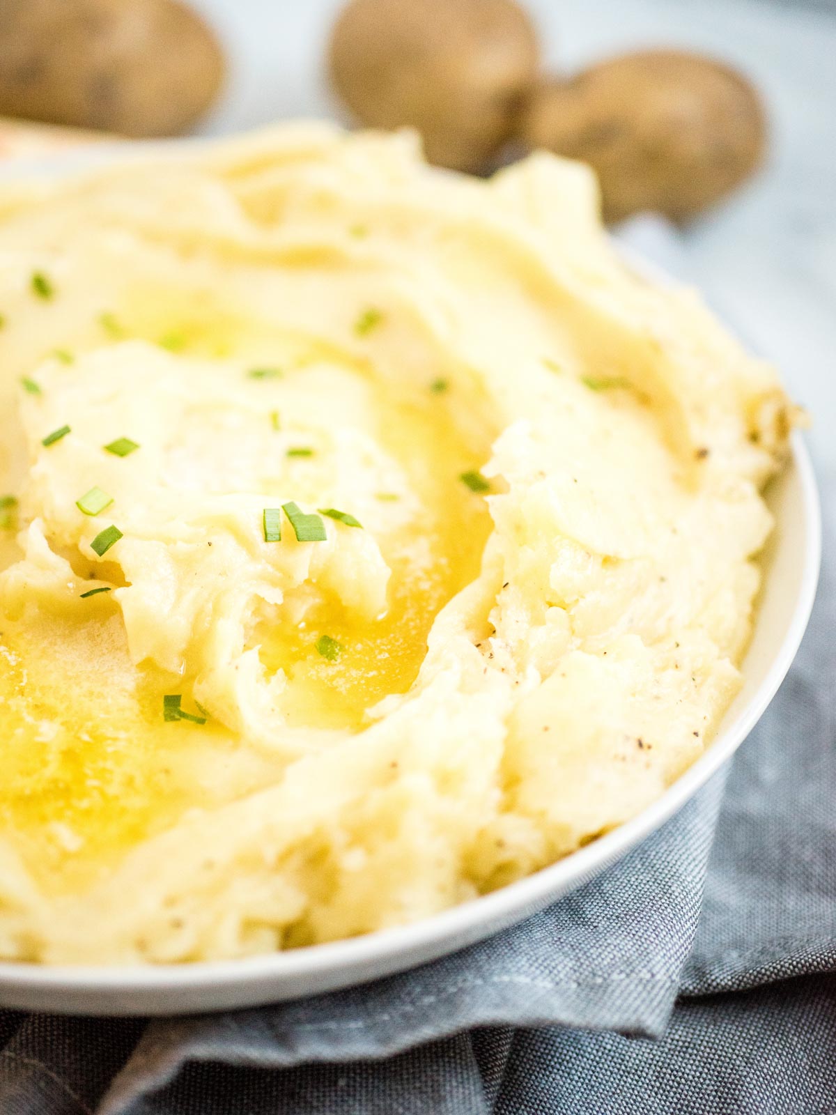 mashed potatoes in white dish topped with melted butter