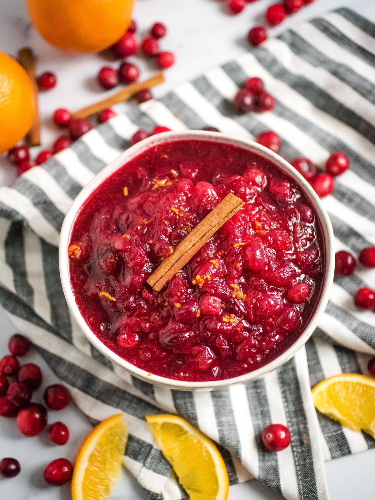 bowl of instant pot orange cranberry sauce surrounded by orange slices and cranberries