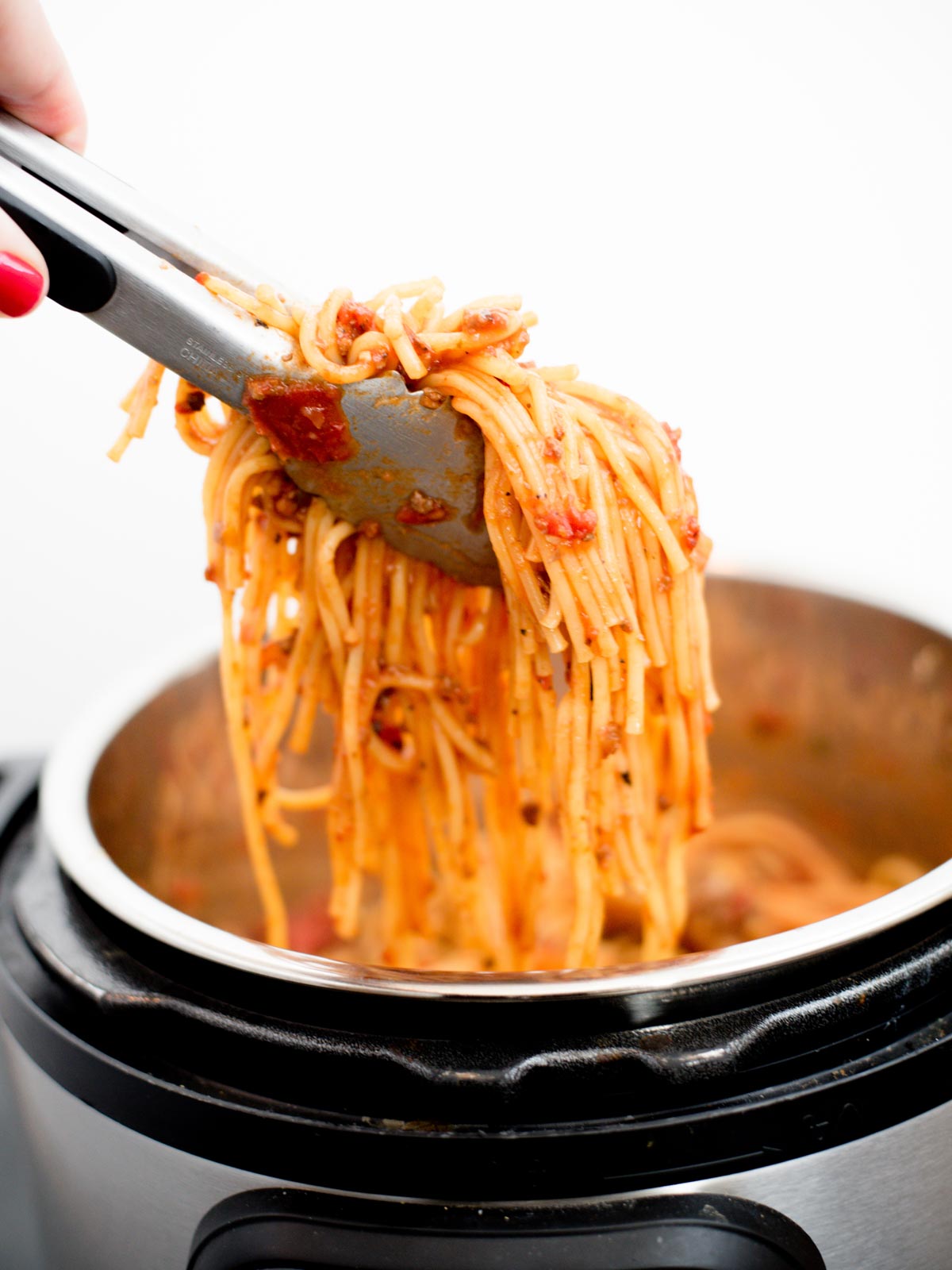 spaghetti being pulled from instant pot with tongs