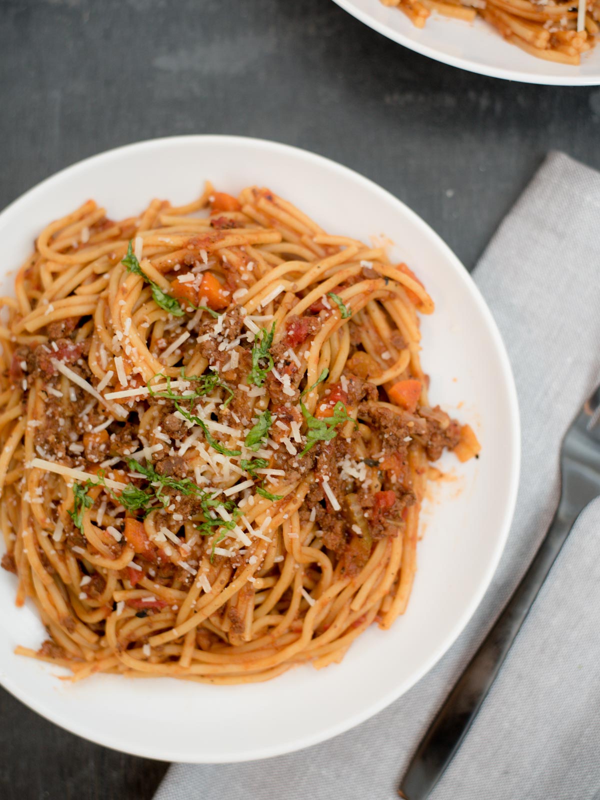 instant pot spaghetti and meat sauce on a white plate topped with parmesan and basil