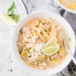 a white bowl full of instant pot white chicken chili with a spoon inside
