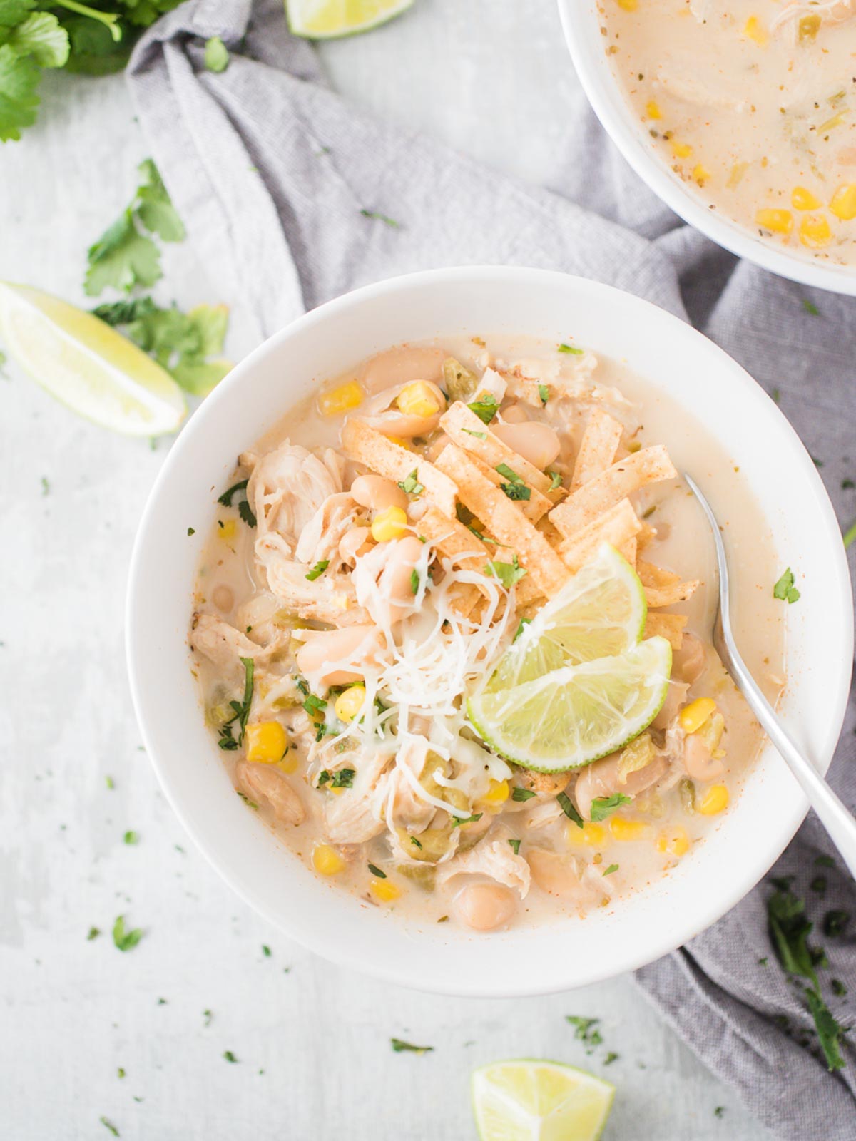 a white bowl full of instant pot white chicken chili with a spoon inside