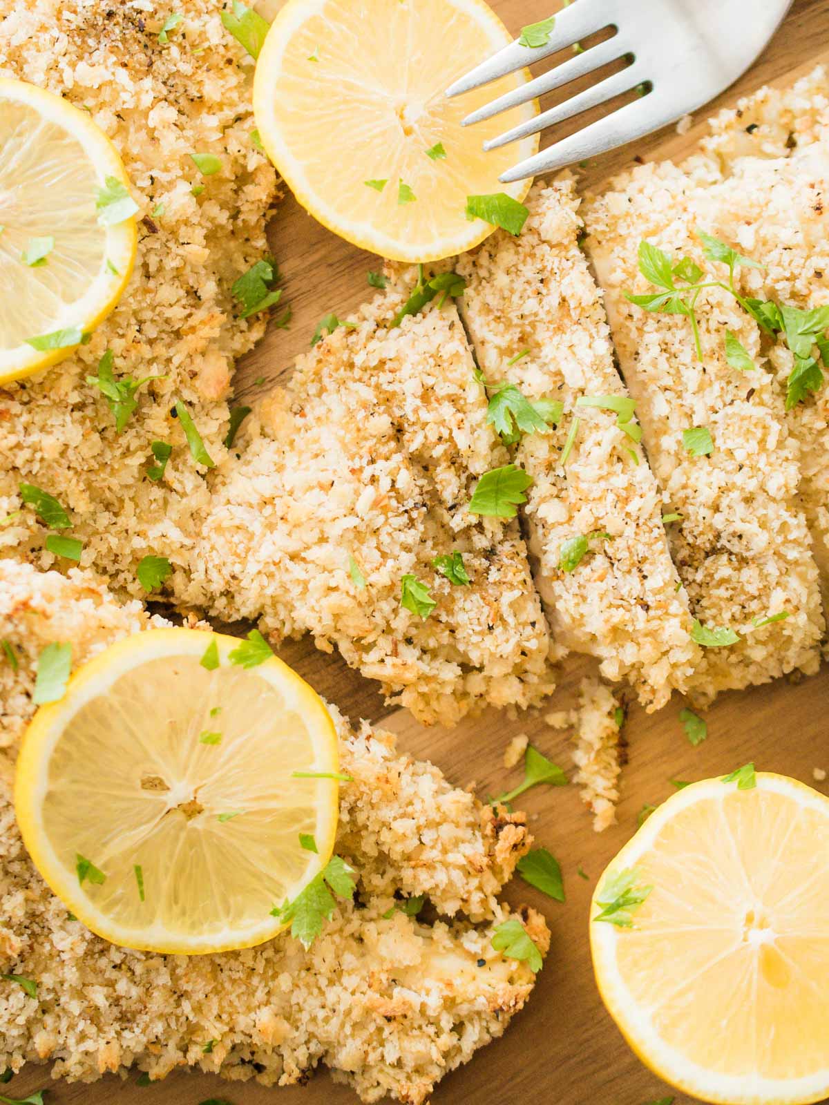 overhead shot of sliced lemon pepper chicken topped with parsley and lemon