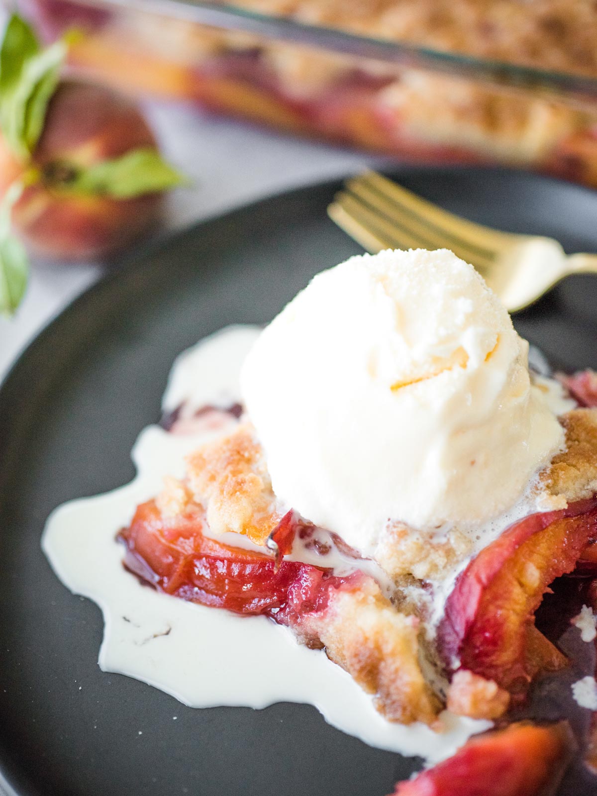 peach cobbler on a plate topped with vanilla ice cream