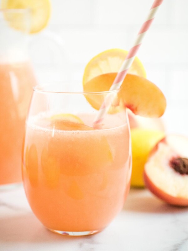 a glass of peach lemonade with a straw