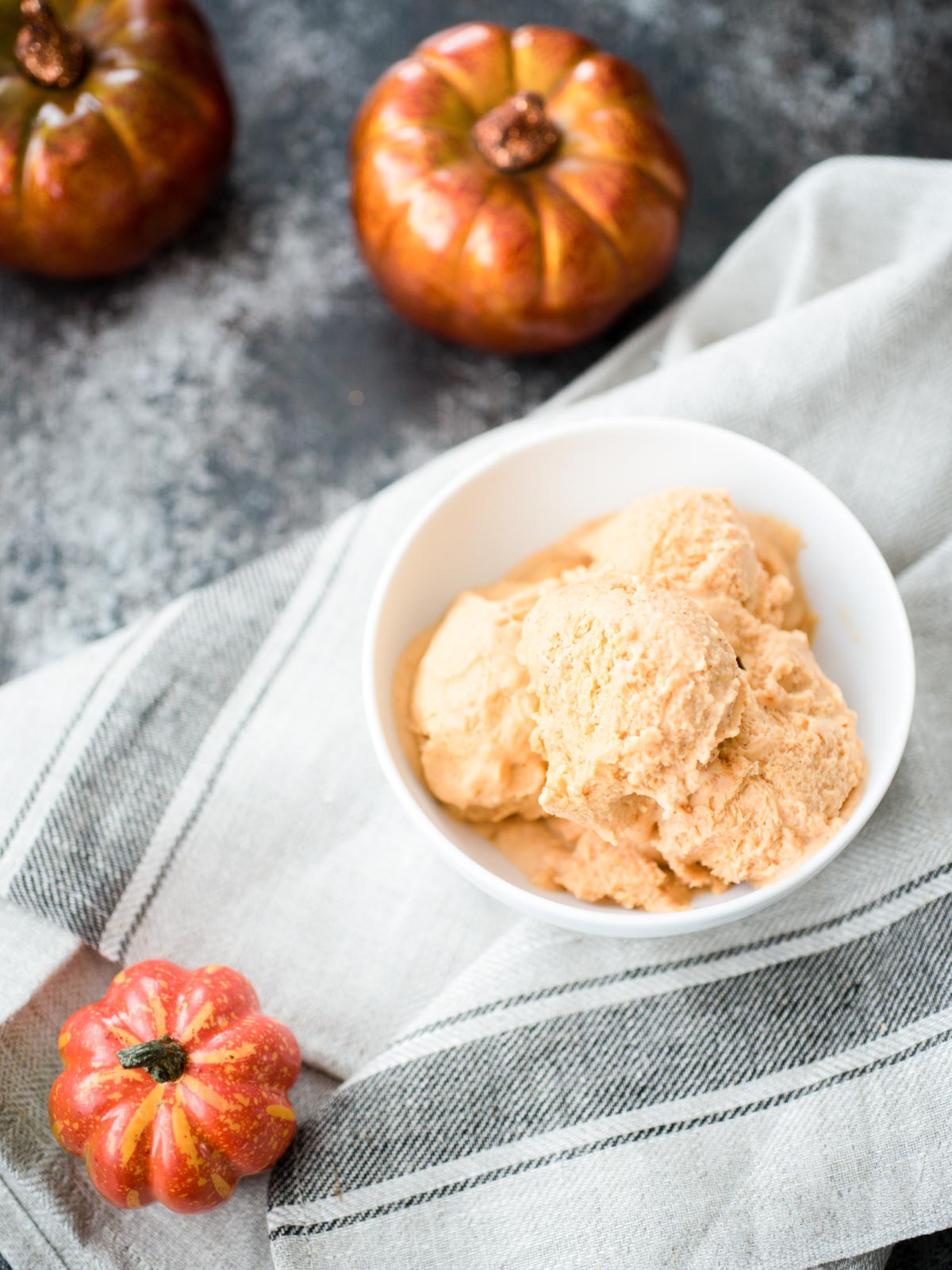 Baby pumpkin sitting next to pumpkin ice cream in a bowl.