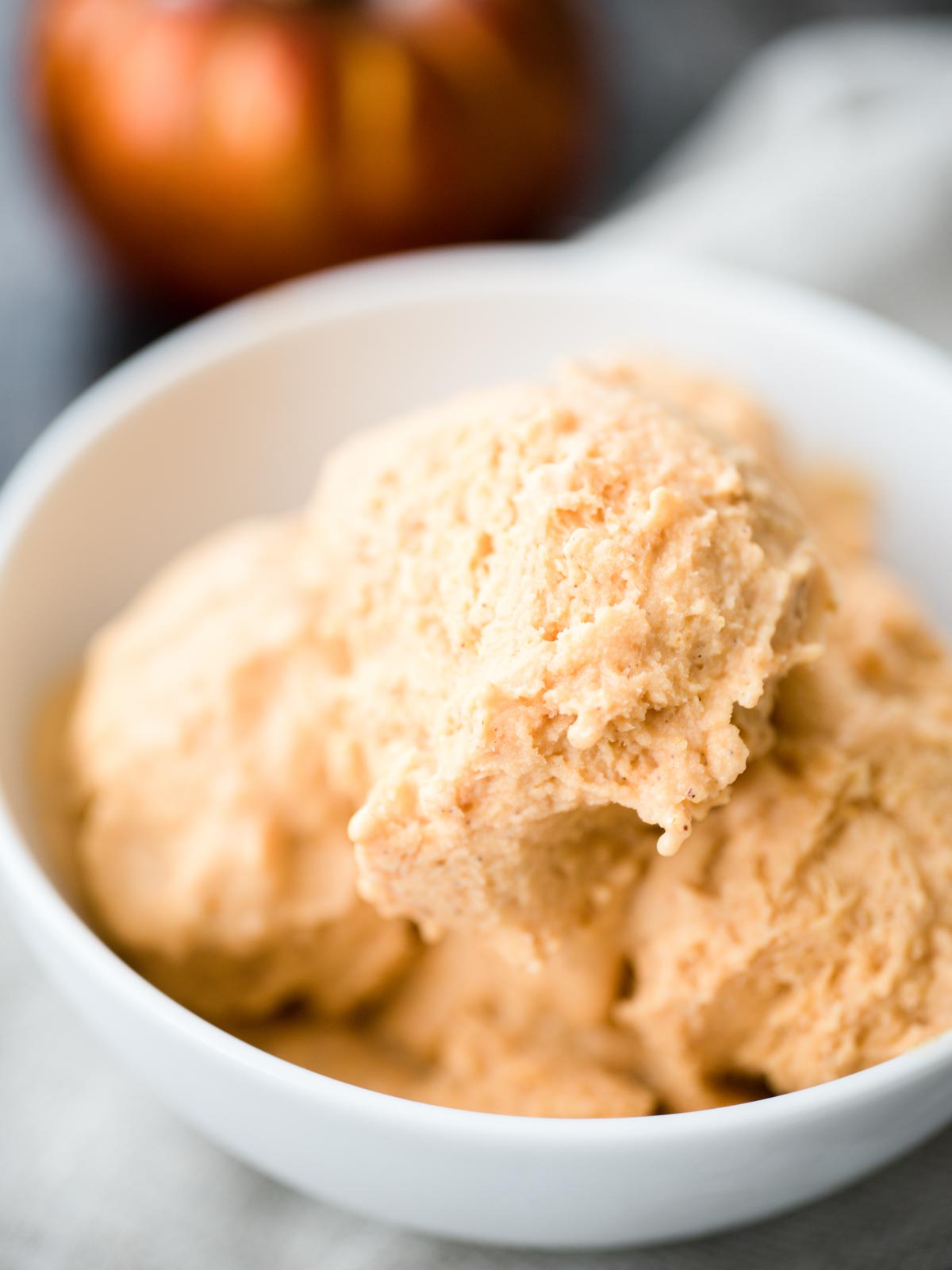 Pumpkin scoops of ice cream in a bowl.