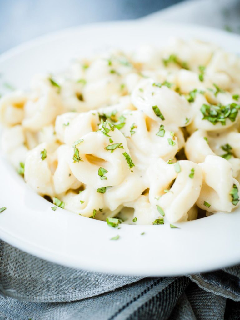 pasta covered in sauce and basil in a bowl