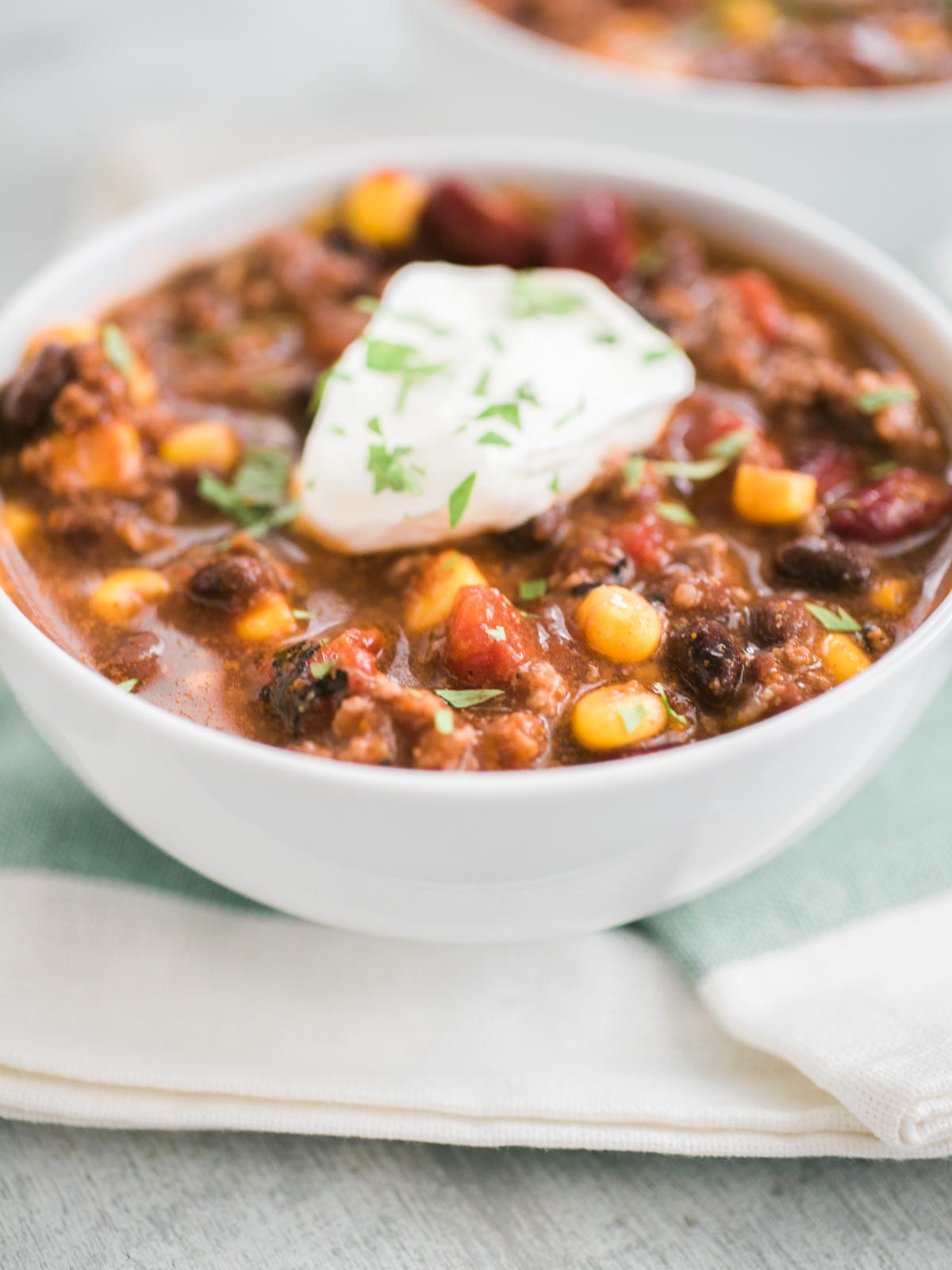 slow cooker taco soup in a white bowl topped with sour cream