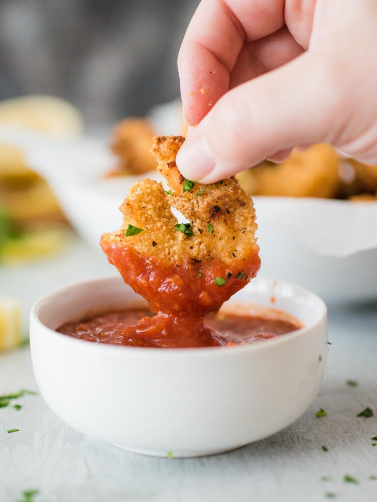 air fried shrimp being dipped in cocktail sauce