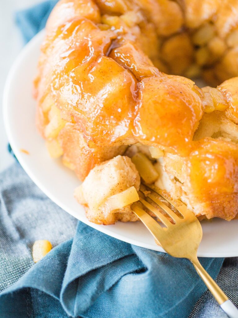 apple cinnamon monkey bread on white plate with gold fork piercing a piece