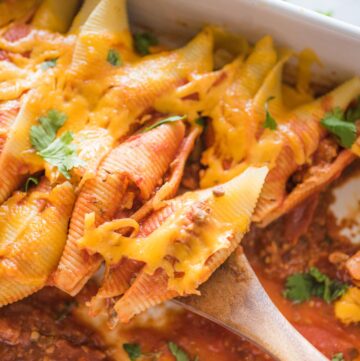 taco stuffed shells being scooped with a wooden spoon