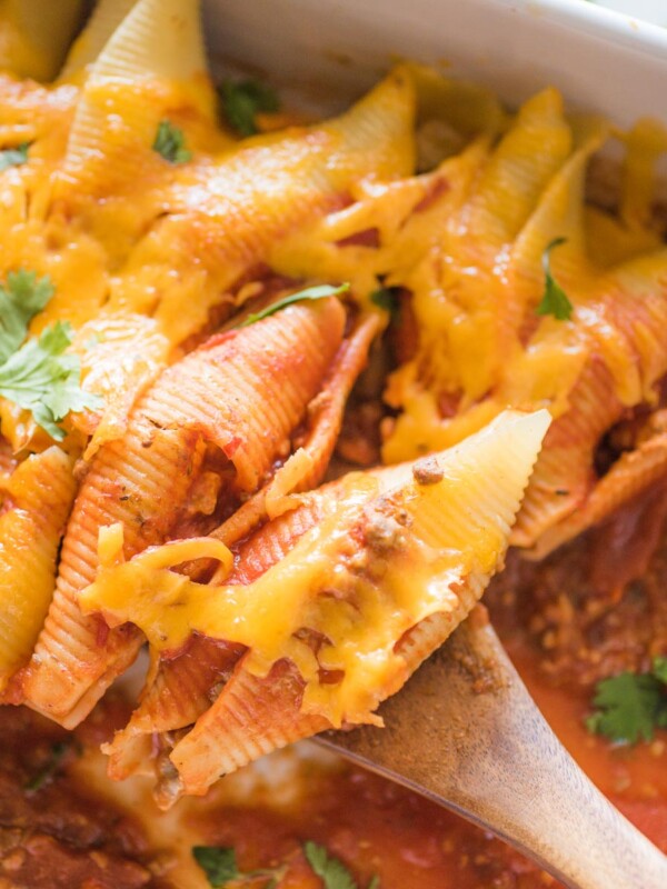 taco stuffed shells being scooped with a wooden spoon