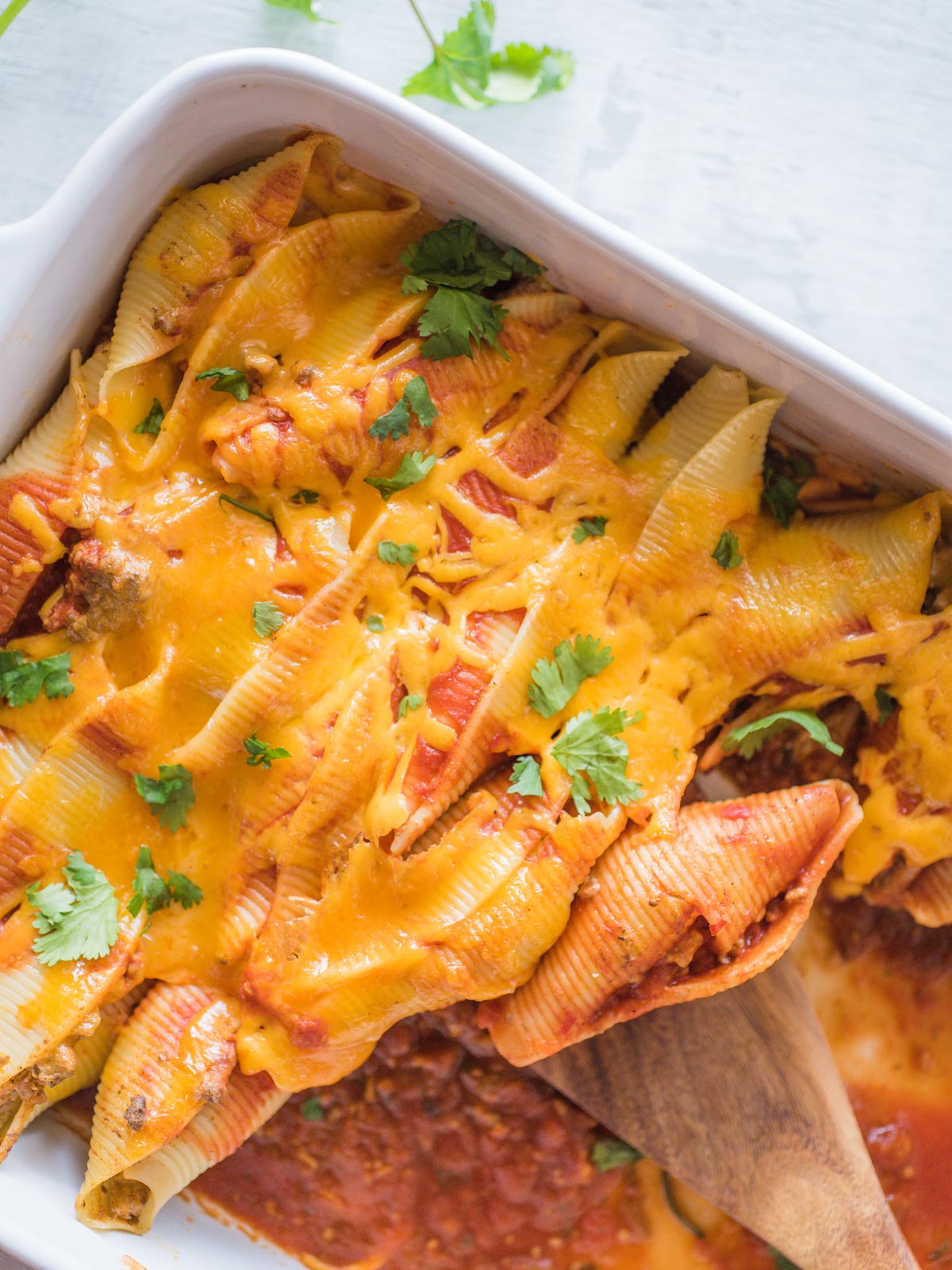 taco stuffed shells being scooped with a wooden spoon