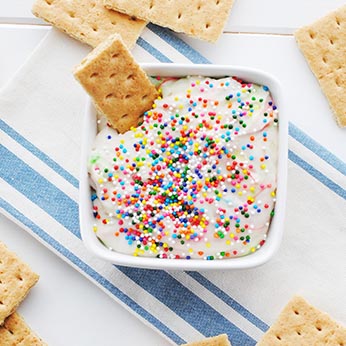 funfetti dip in a bowl surrounded by graham crackers