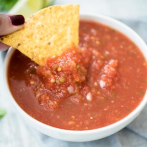salsa in a bowl being dipped with a chip