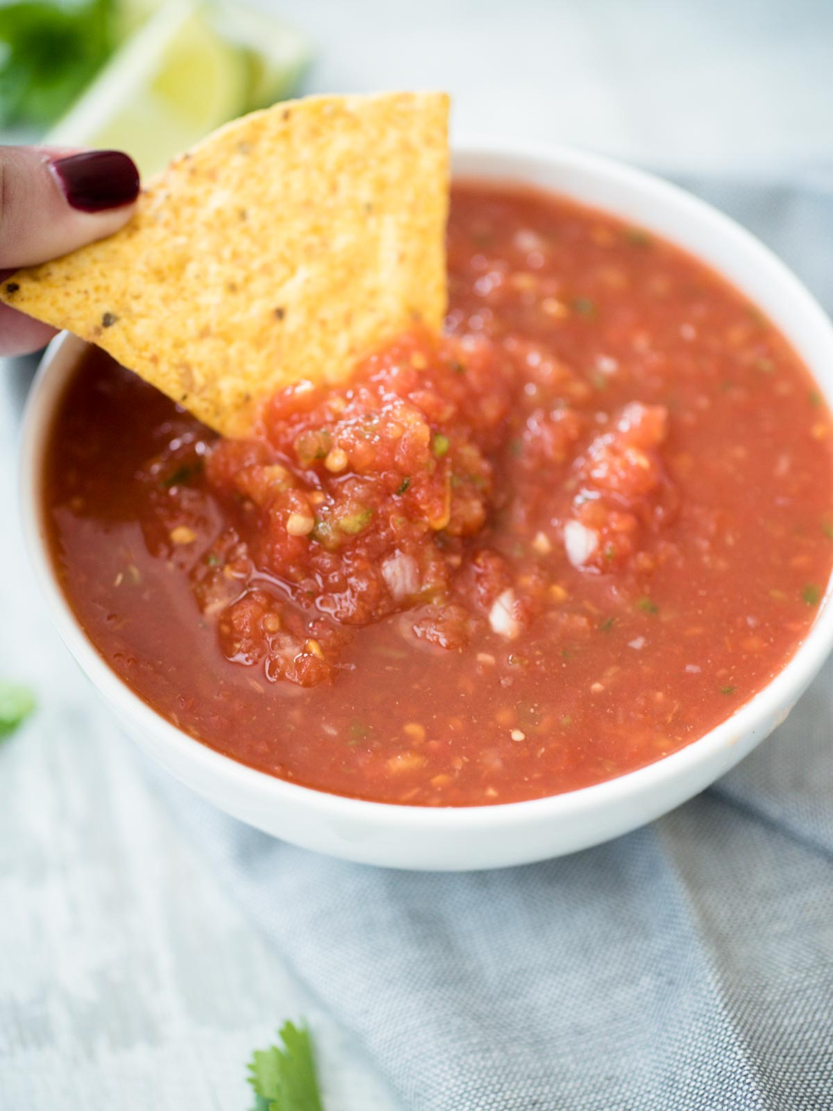 salsa in a bowl being dipped with a chip