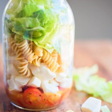 Italian Mason Jar Salad in a jar surrounded by various ingredients on a table