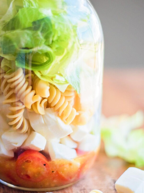 Italian Mason Jar Salad in a jar surrounded by various ingredients on a table