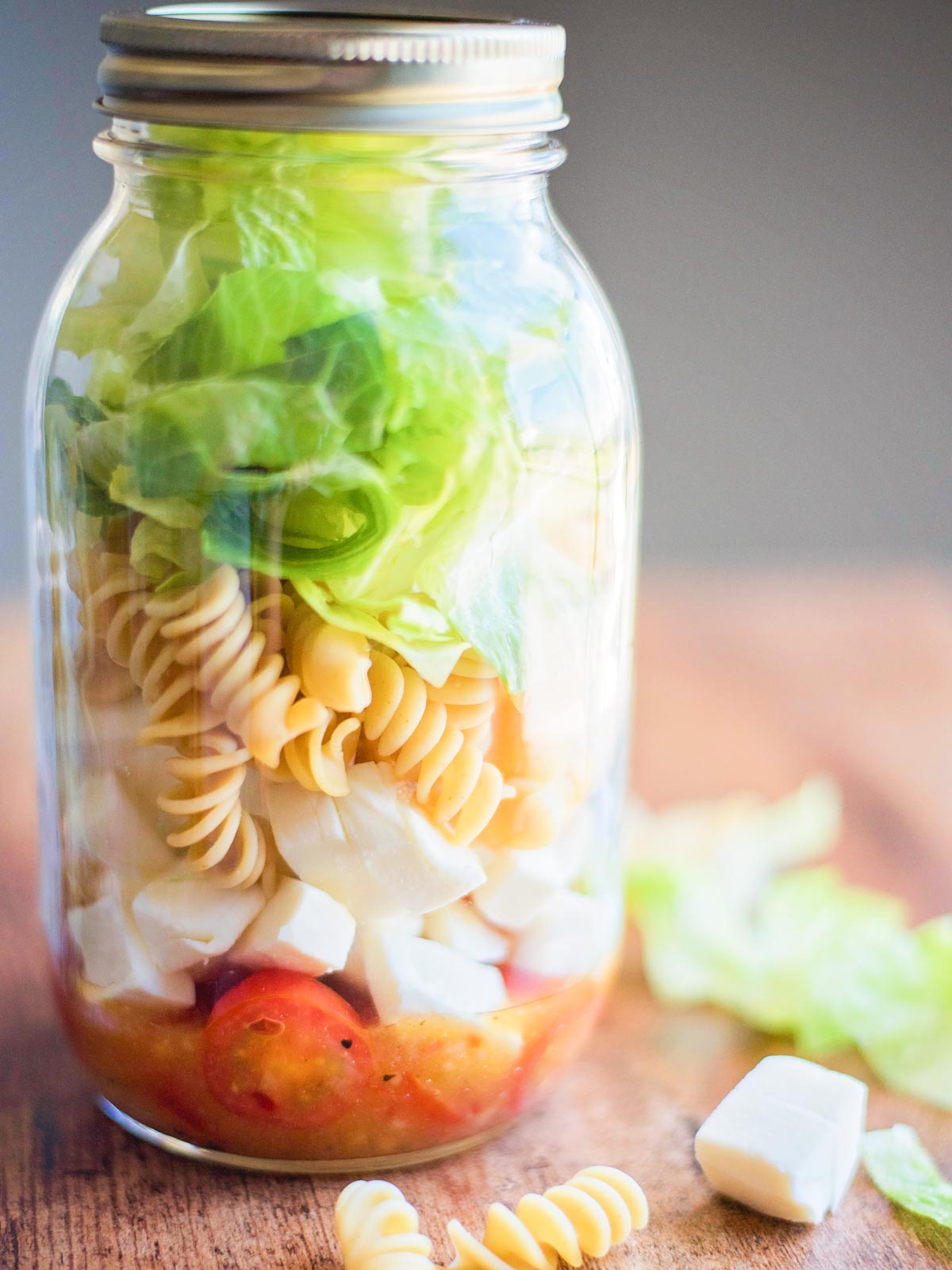 Italian Mason Jar Salad in a jar surrounded by various ingredients on a table