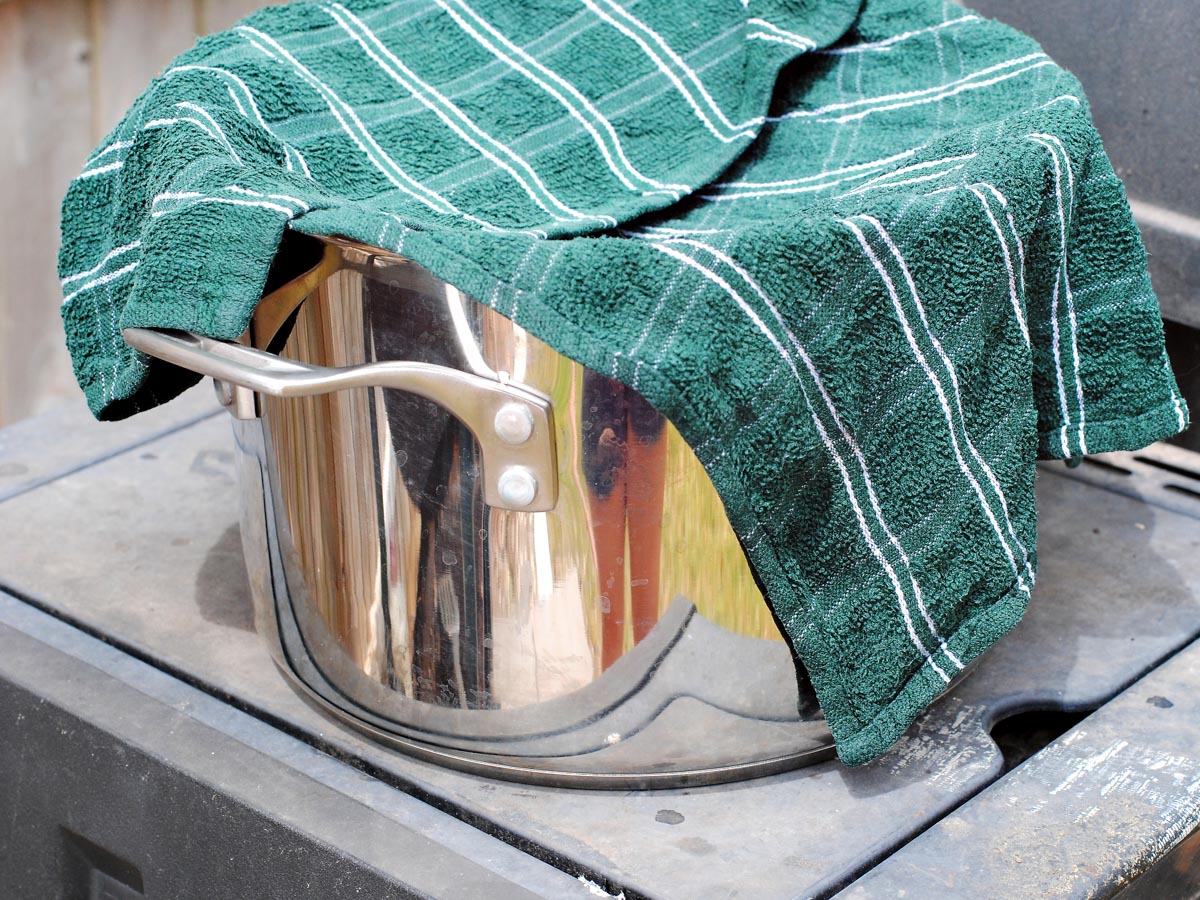 a silver pot with a green dish towel over it